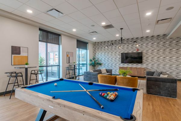 A stylish game room featuring a modern pool table, lounge seating, and warm lighting for residents to relax and have fun at District Flats Columbia.