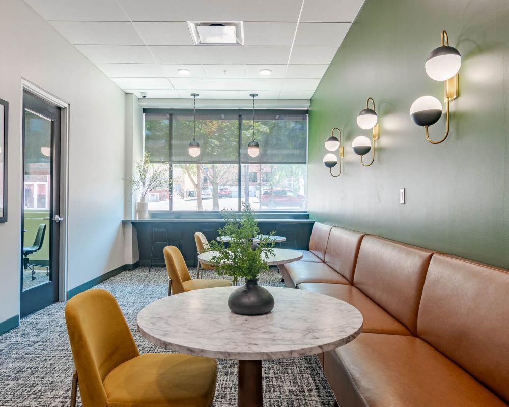 A bright and modern study room with large windows, orange chairs, and cozy seating, designed for focused productivity at District Flats Columbia.